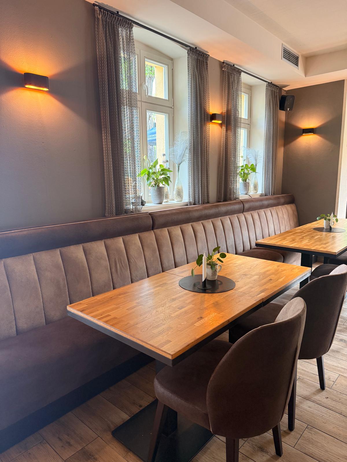 Holztische und gepolsterte Sitzbank neben den Fenstern im Restaurant Grashorn