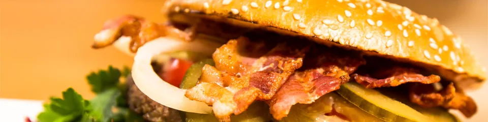 Burger im Sesambrötchen mit Bacon, Zwiebeln und Salat