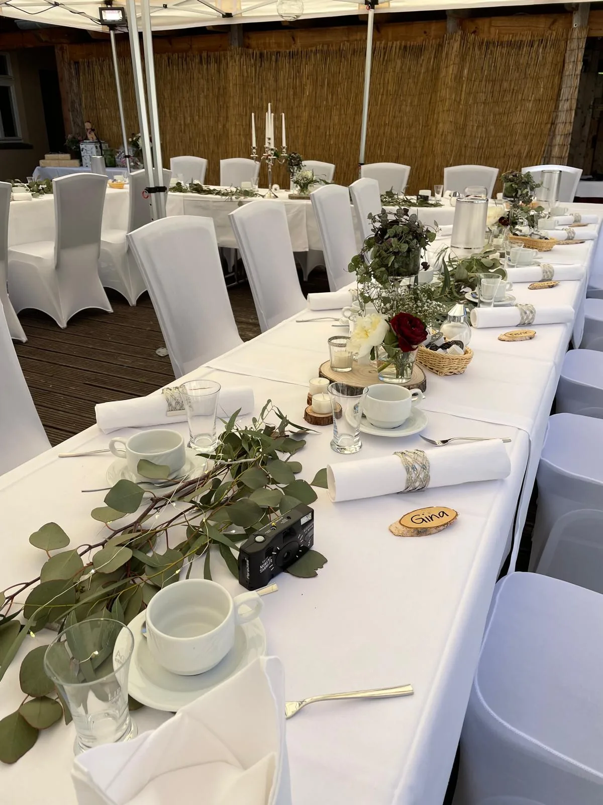 Festlich gedeckte Hofterrasse mit weißen Stuhlhussen und Blumenschmuck