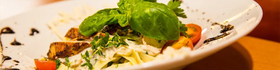 Angerichtetes Pastagericht mit Gemüse und Basilikum