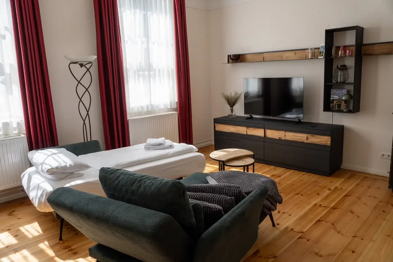 Wohn- und Schlafbereich mit Doppelbett, Sofa und Esstisch im Apartmenthaus Gutenberg 78